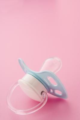 a baby pacifier sitting on top of a pink table