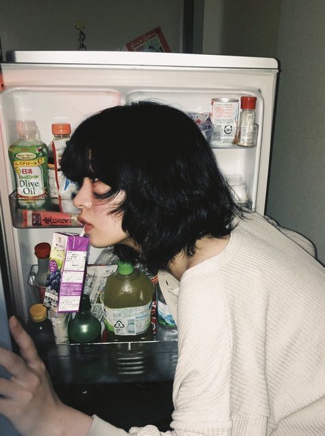 a woman is looking into an open refrigerator