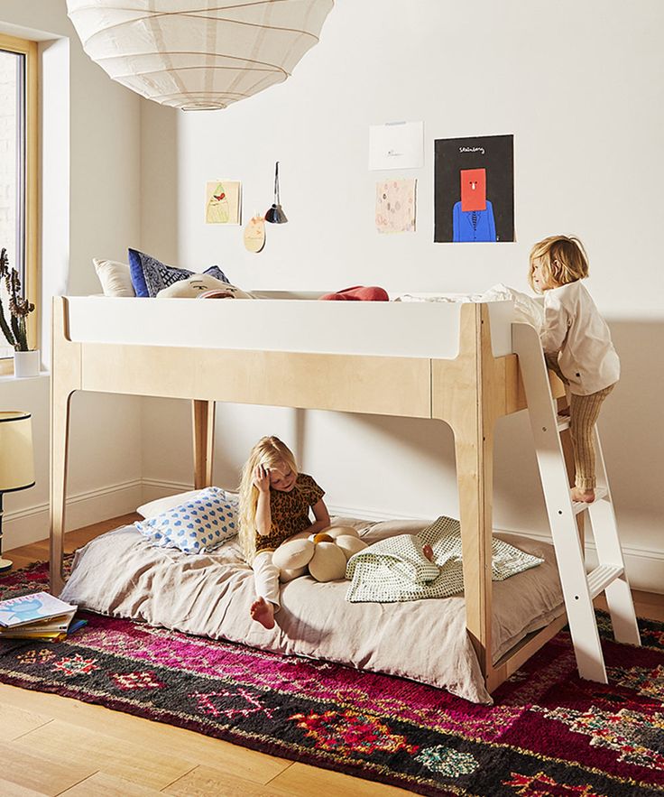 two children are sitting on the bottom bunk of a bed and one is playing with a toy