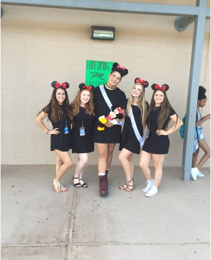 a group of people standing next to each other in front of a building with mickey mouse ears on their heads