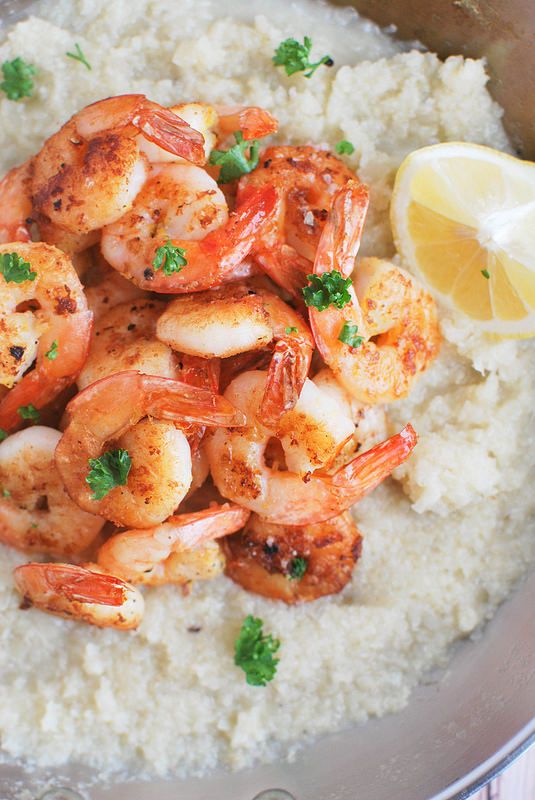 shrimp and rice with lemon wedges on the side in a pan, garnished with parsley