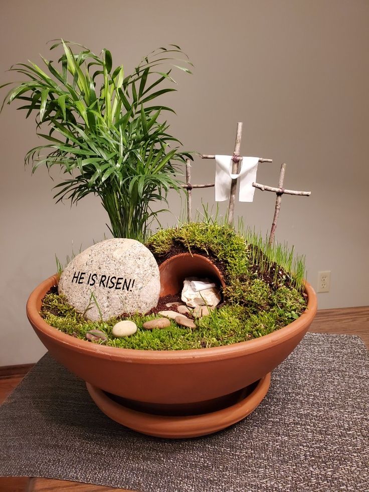 a potted plant sitting on top of a table next to a rock and cross