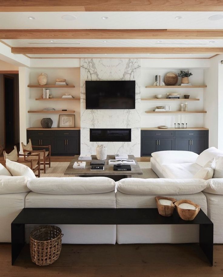 a large white couch sitting in a living room next to a tv mounted on a wall