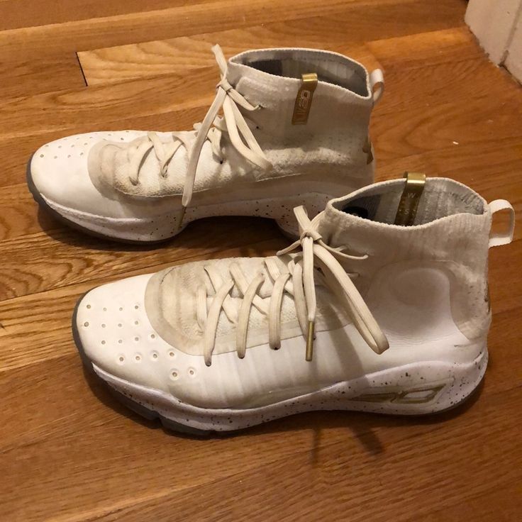 a pair of white shoes sitting on top of a wooden floor