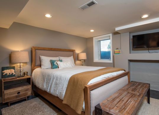 a bedroom with a bed, dresser and television on the wall next to a fireplace