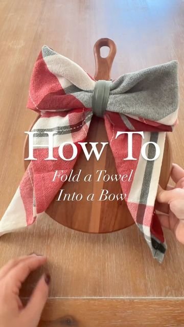 someone is holding a bow on top of a wooden board with the words how to fold a towel into a bow