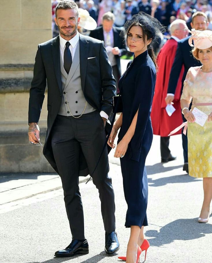 a man and woman walking down the street in formal attire with hats on their heads