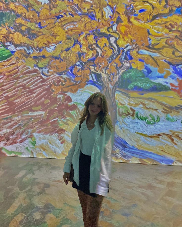 a woman standing in front of a large painting