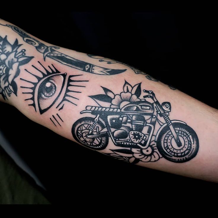 a man's arm with an eye and motorcycle tattoo on it