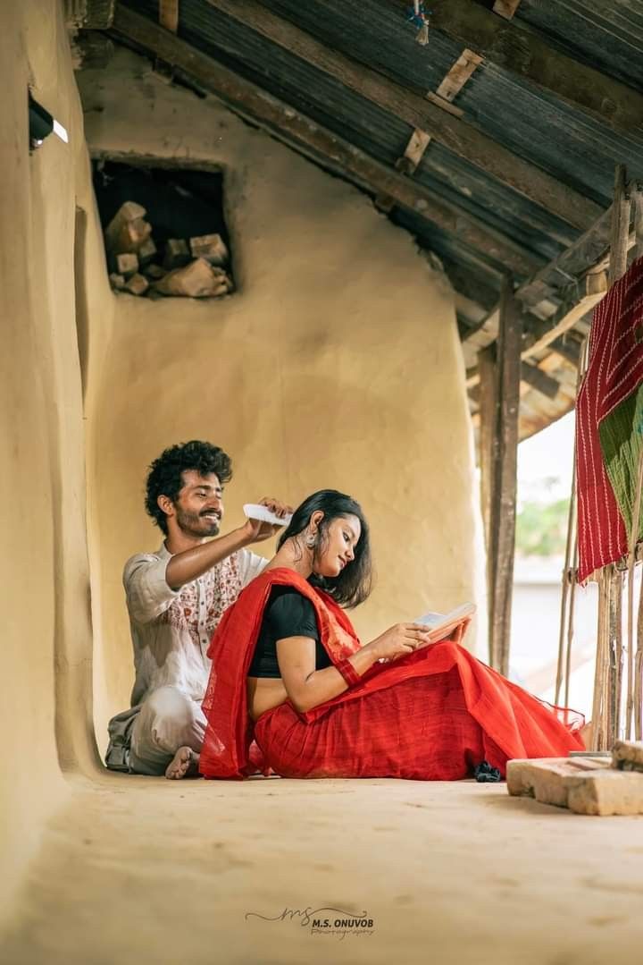 a man and woman sitting on the ground in front of an adobe building, one brushing her hair