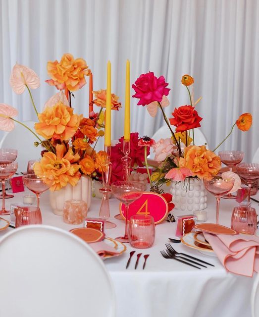 the table is set with pink and orange flowers