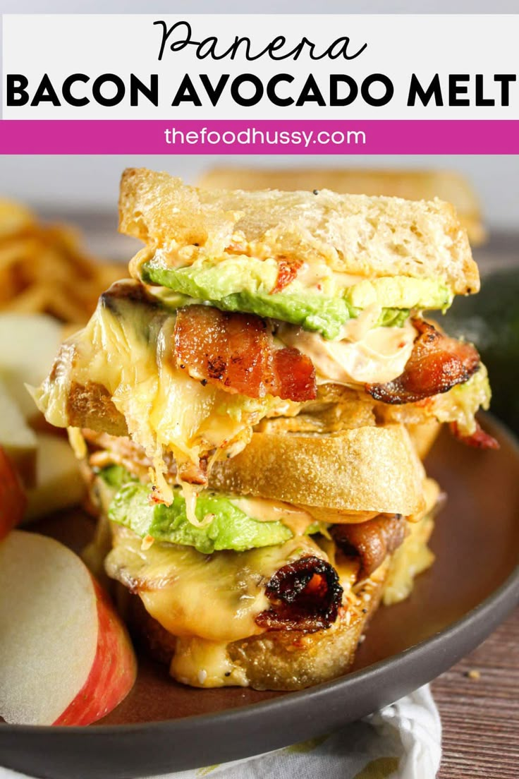 bacon avocado melt sandwich stacked on top of each other with apples in the background