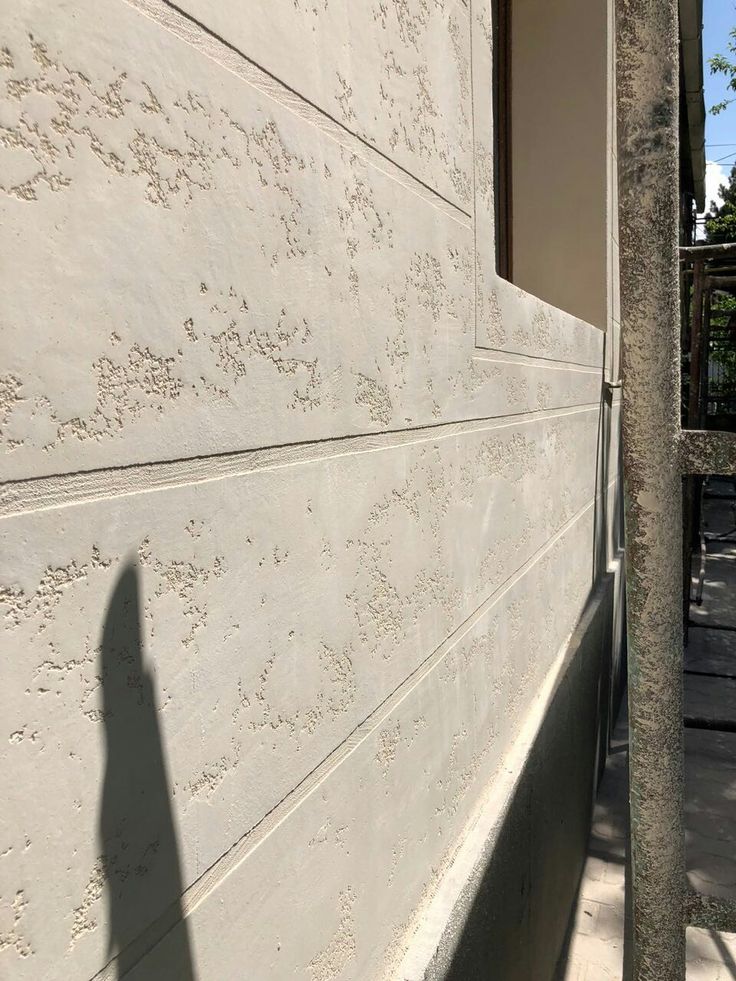 the shadow of a person standing in front of a building on a sidewalk next to a tree