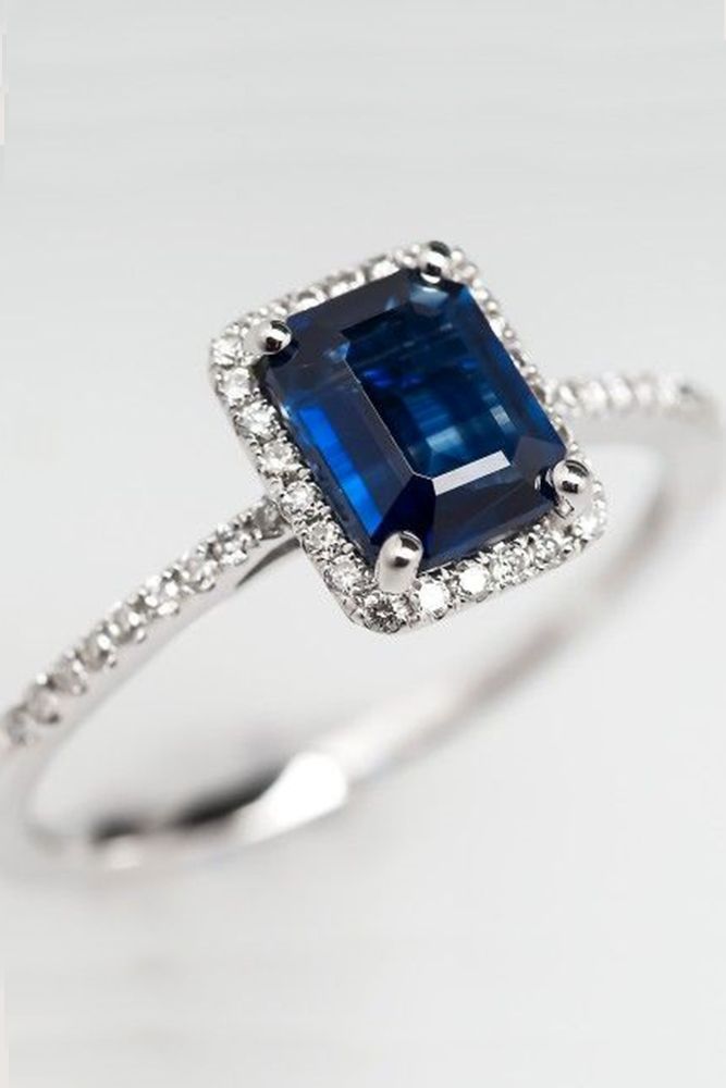 an engagement ring with a blue sapphire and diamonds on the band, set in white gold