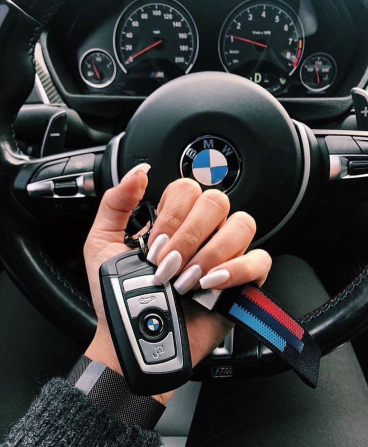 a woman driving a car with her hands on the steering wheel and holding a cell phone