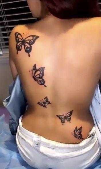 the back of a woman's body with butterflies on her upper and lower back