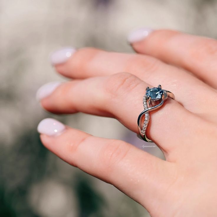 The entwined lovers knot is a symbol of everlasting devotion. This ring is perfect to wear as engagement ring, promise ring, birthstone ring, or statement piece.►Average band width: 2.3 mm►True to size.Center Stone: AquamarineColor: BlueGemstone creation: lab-created Shape: RoundMeasurements: 6.0 mmCarat Weight: 1.1 ct. (approx.)Cut: BrilliantAccent stones: Simulated diamonds (CZ)✓ Comfort Fit✓ Free Ring Box✓ Free USA Shipping✓ Ready to ship next business day Solitaire Birthstone Open Ring For Promise, Promise Rings With Center Stone And Open Ring Design, May Birthstone Diamond Ring With Center Stone For Promise, White Gold Crystal Promise Ring For May Birthstone, Solitaire Promise Ring With May Birthstone, Promise Ring With May Birthstone In Round Cut, Promise Diamond Ring With May Birthstone Center Stone, Promise Diamond Ring With May Birthstone, Promise Diamond Ring With Center Stone For May Birthstone