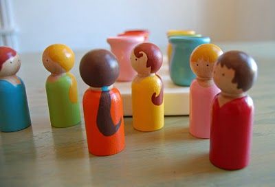 a group of small wooden toy figures sitting on top of a table next to each other