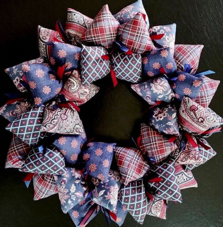 a wreath made out of fabric on top of a black surface with red, white and blue ribbons