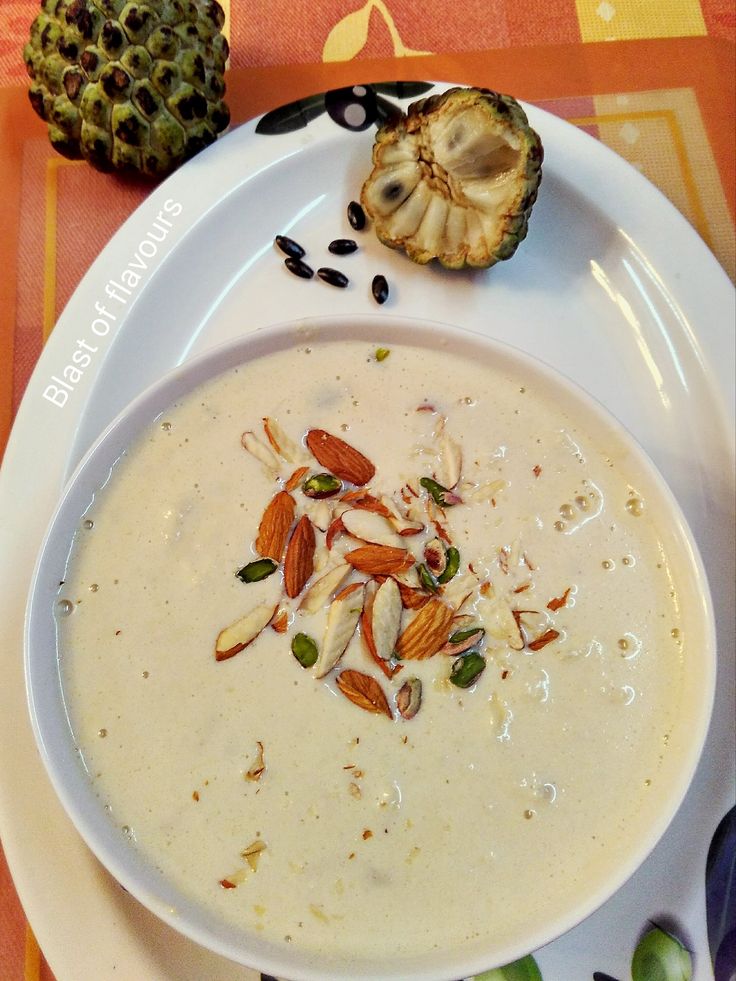 a white plate topped with a bowl of soup next to a pineapple on top of a table