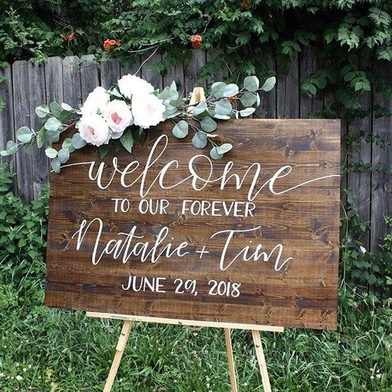 a wooden sign with flowers on it sitting in the grass