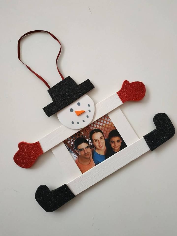 a snowman ornament hanging from a string on a white surface with red and black hearts