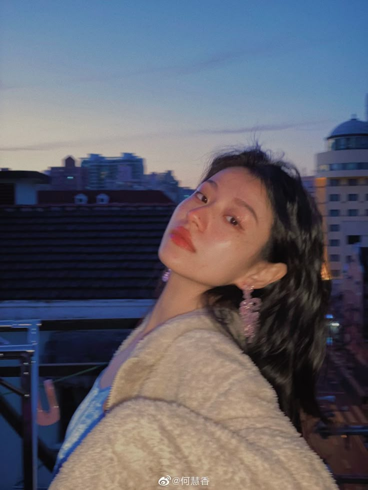 a woman standing on top of a roof next to a tall building with buildings in the background