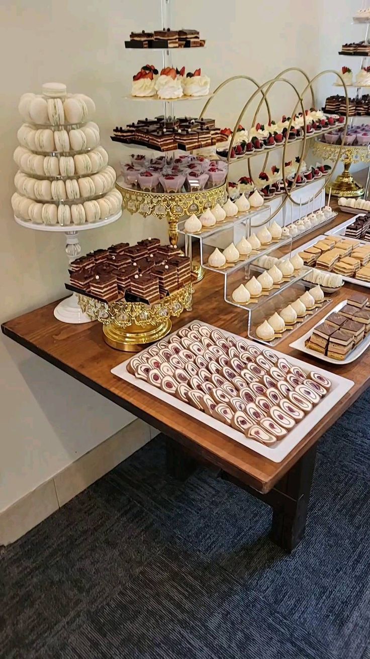 a table topped with lots of desserts and pastries next to a wall mounted display