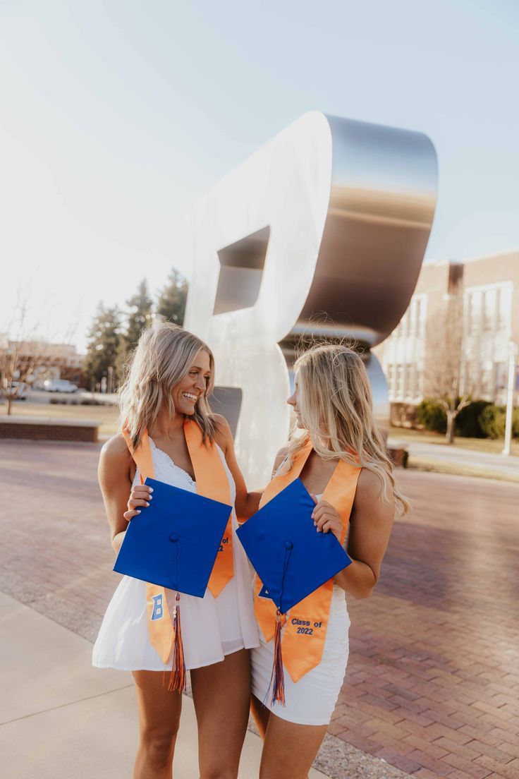 two women standing next to each other in front of a sculpture