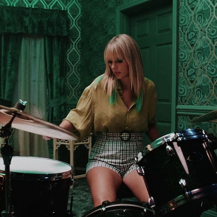 a woman sitting in front of a drum set