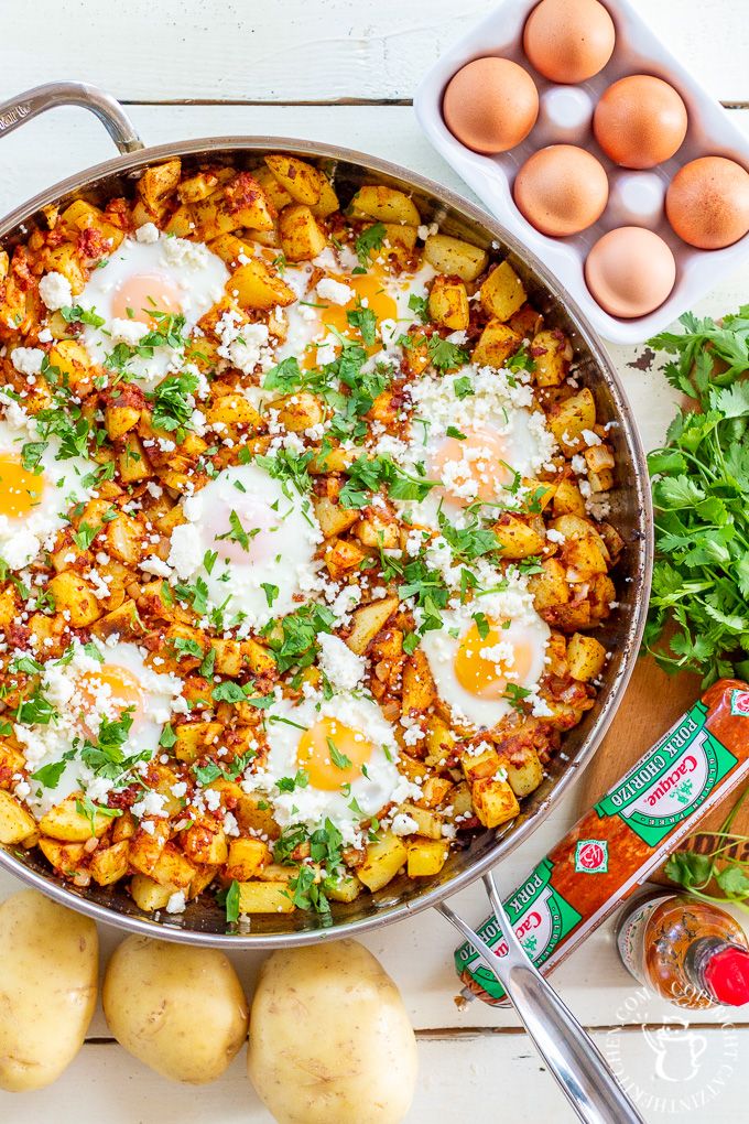 eggs, potatoes and parsley in a pan on a white wooden table with other ingredients