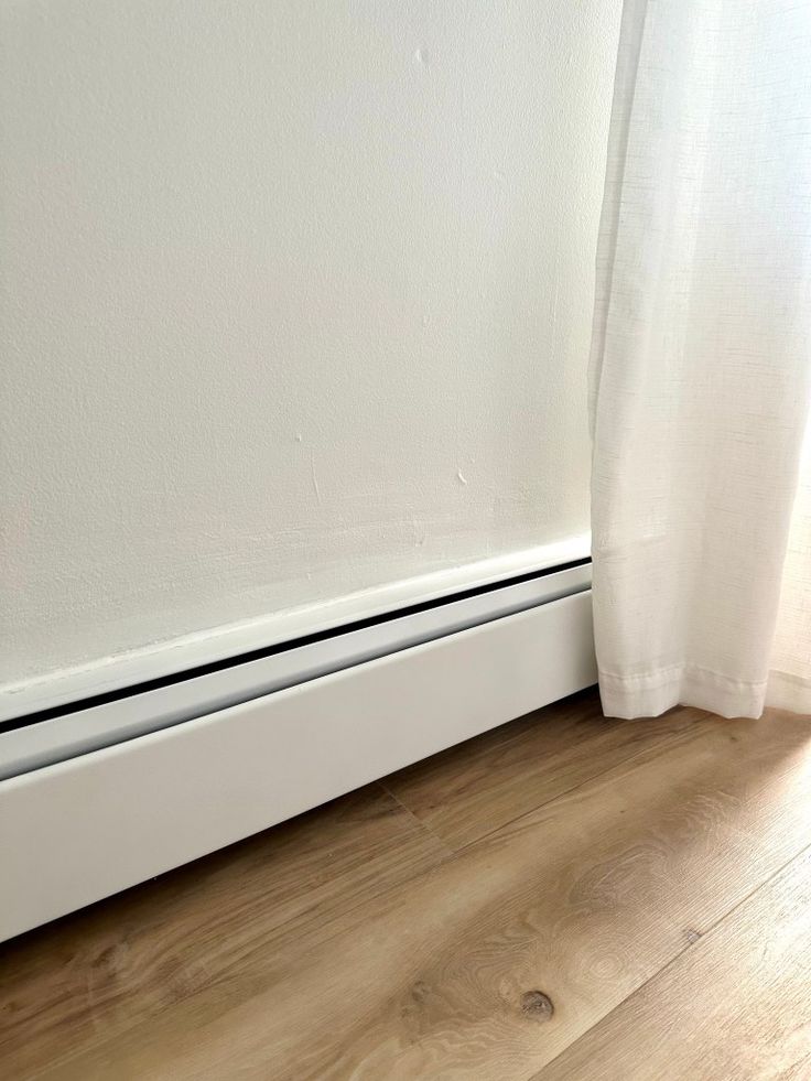 a white radiator sitting on top of a wooden floor next to a window