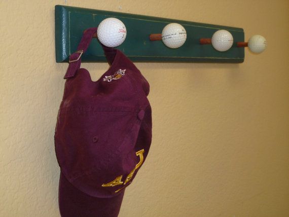 a baseball hat hanging on a wall with three balls attached to the back of it