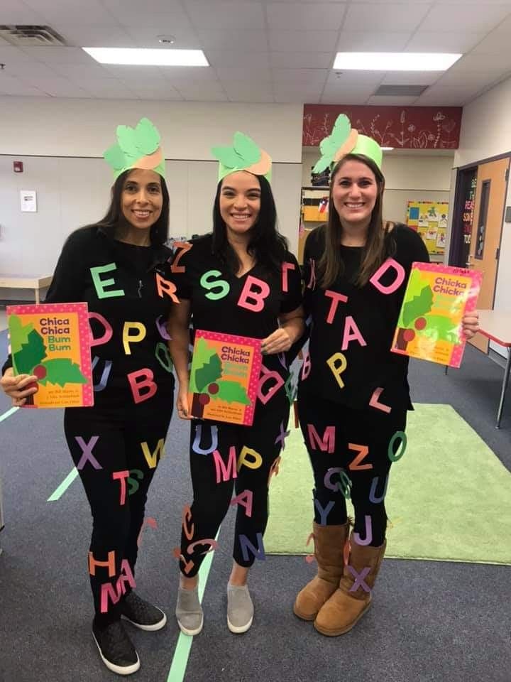 three girls in matching outfits hold up signs that spell out the word'alphabet '