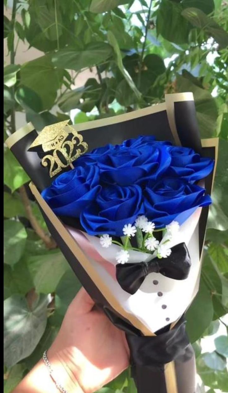 a bouquet of blue roses in a black and white box with a gold crown on top