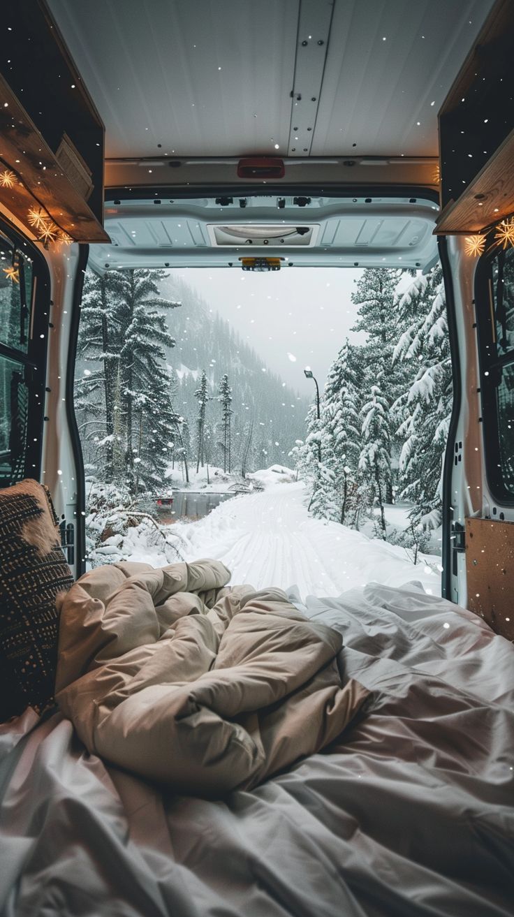 the inside of a camper van is covered with blankets and pillows as it sits in the snow