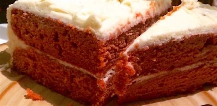 two slices of red velvet cake with white frosting sitting on a wooden platter