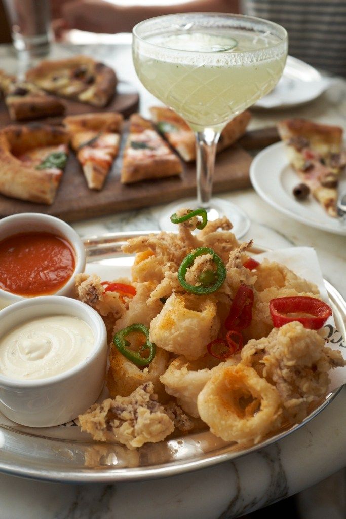 a plate full of food with sauces and pizza on the table next to it