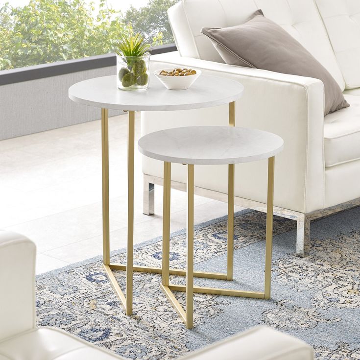 two tables sitting on top of a blue rug in front of a white couch and chair