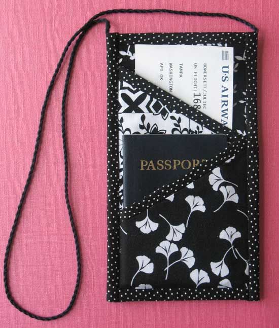 a black and white passport case sitting on top of a pink surface