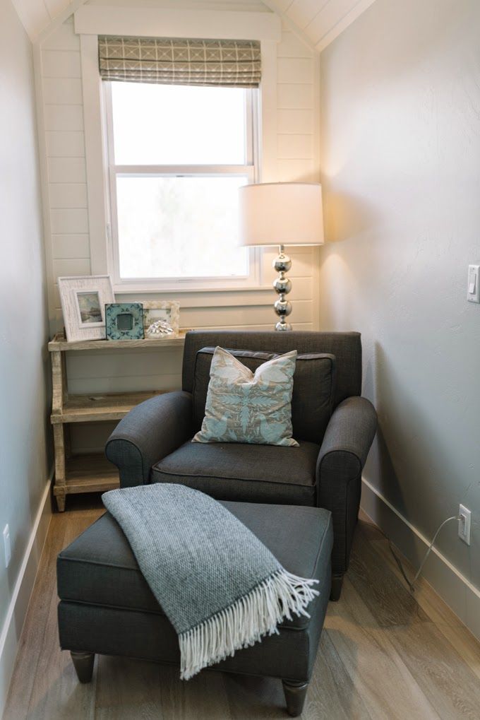 a chair and ottoman in a room with wood flooring, white walls and windows