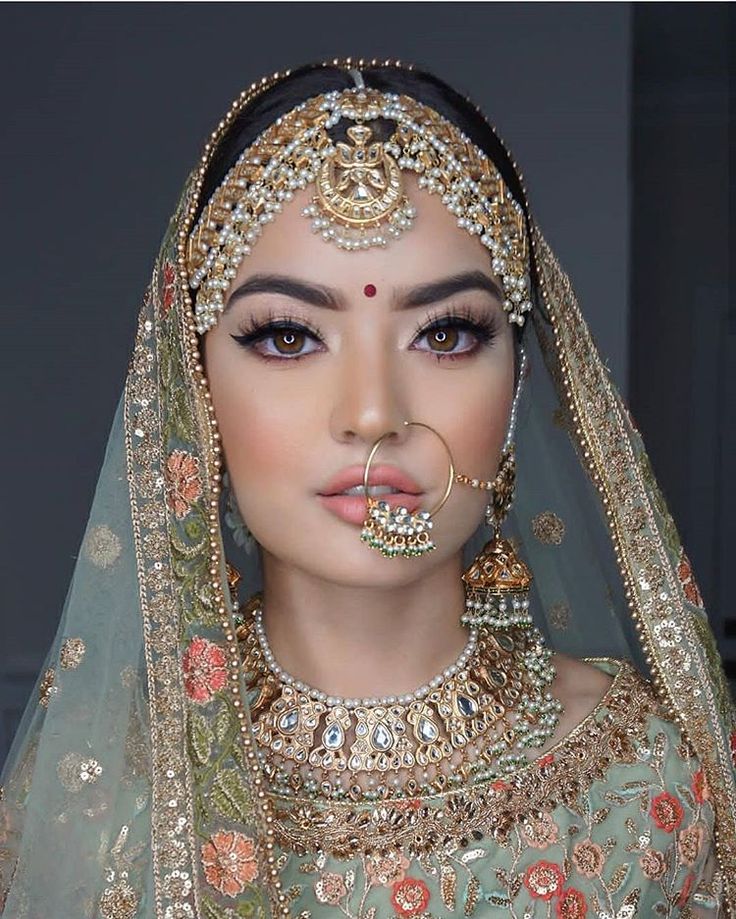 a woman in a bridal outfit with jewelry on her face and nose piercings