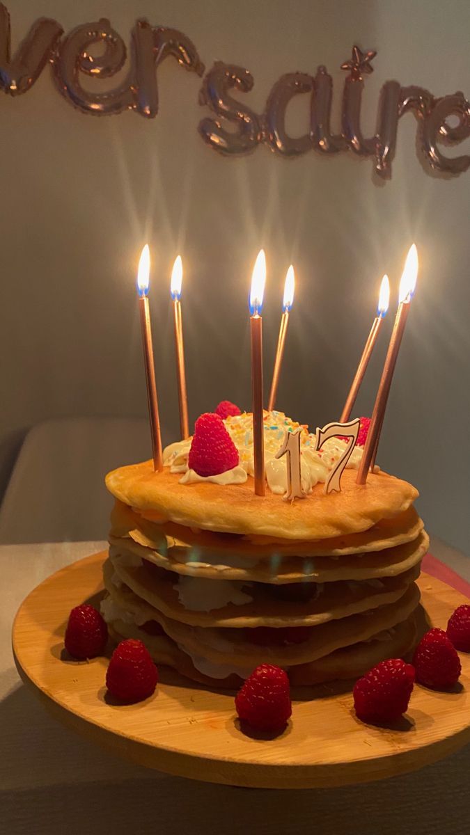 a stack of pancakes with lit candles and strawberries