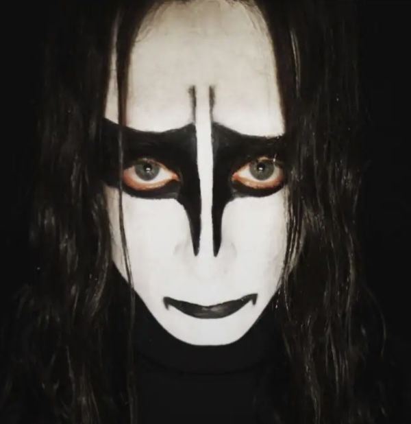 a man with long black hair and white face paint