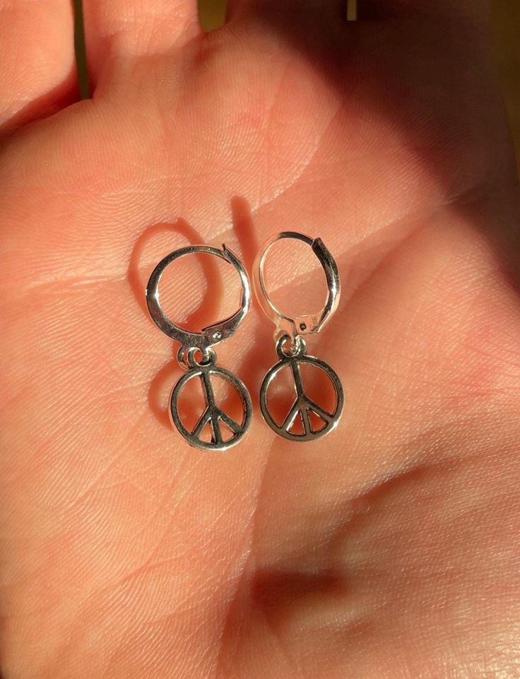 Mini Peace Sign Hoop Earrings Embrace tranquility with our Mini Peace Sign Hoop Earrings, the perfect blend of elegance and sentiment. These delicate hoops, crafted from high-quality, hypoallergenic metal, feature a dainty peace sign charm that adds a touch of boho-chic to any outfit. The minimalist design ensures they're versatile enough to transition seamlessly from day to night, while their lightweight feel makes them ideal for all-day wear.  Ideal for those who love subtle, meaningful accessories, these earrings make a thoughtful gift or a charming addition to your own jewelry collection. Available in a choice of gold, silver, or rose gold finishes, they offer a timeless appeal that's always in style. Embrace peace and positivity with every wear! Peace Sign Jewelry, Peace Sign Earrings, Hippie Mom, Peace Earrings, Hippie Accessories, Mom Earrings, Peace Sign Necklace, Boone Nc, Estilo Hippie