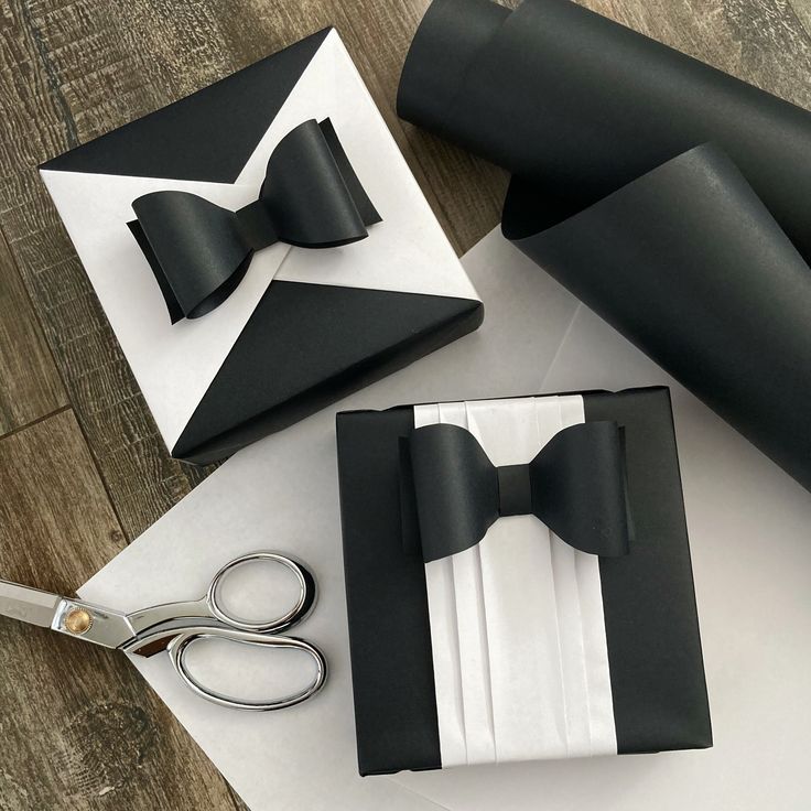 a pair of scissors and some black and white paper with bow ties on it, sitting next to an empty box