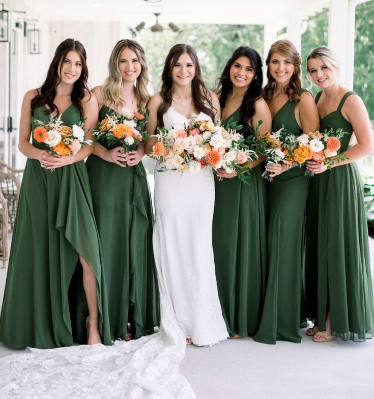 a group of women standing next to each other holding bouquets in their hands and wearing green dresses