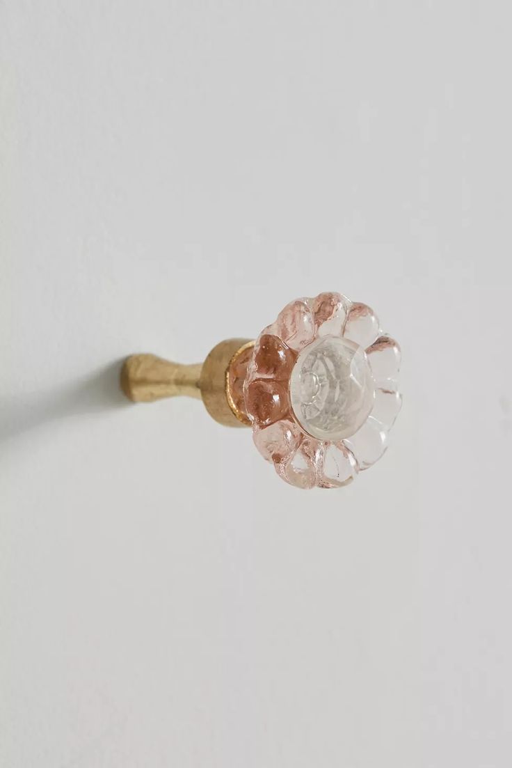 a close up of a flower shaped object on a white surface with a gold handle