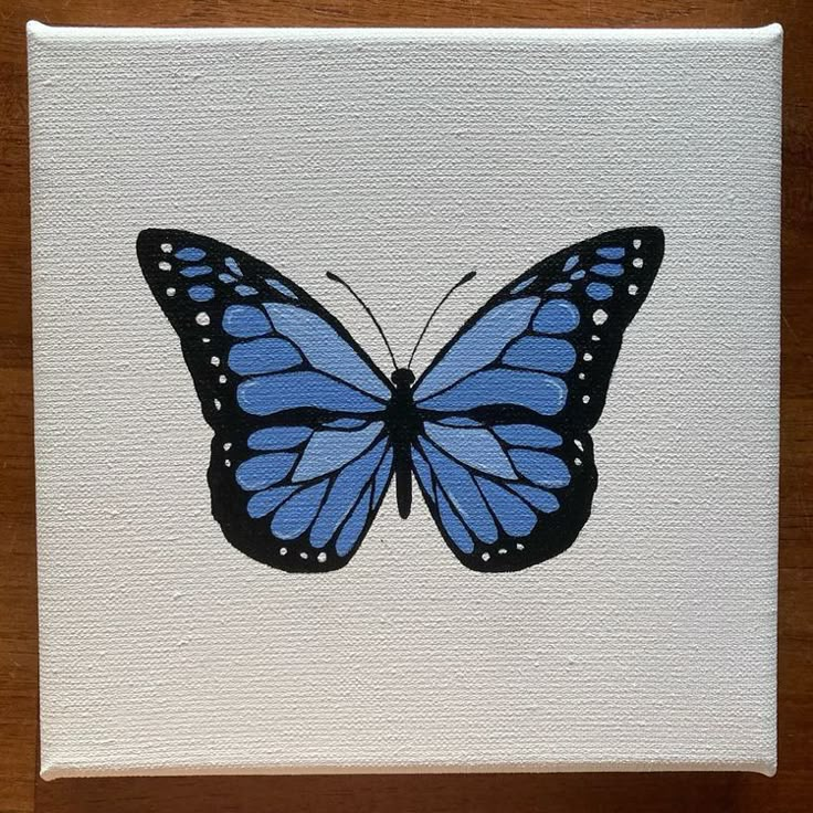 a blue butterfly painted on white paper with wood flooring and wall in the background