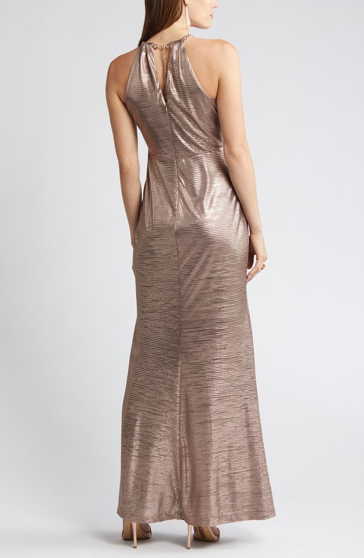 Steal the show in this glamorous metallic gown designed with a golden chainlink neckline and sleek cutaway shoulders. 56" center front length (size 8) Sleeveless, with cutaway shoulders Lined 100% polyester Dry clean Imported Glamorous Metallic Gown For Gala, Elegant Gold Shimmer Evening Dress, Formal Fitted Gown With Shimmer, Glamorous Metallic Evening Gown, Gold Shimmer Floor-length Dress, Metallic Maxi Evening Dress For Gala, Metallic Maxi Length Evening Dress For Gala, Metallic Maxi Dress For Gala, Metallic Floor-length Maxi Dress For Gala